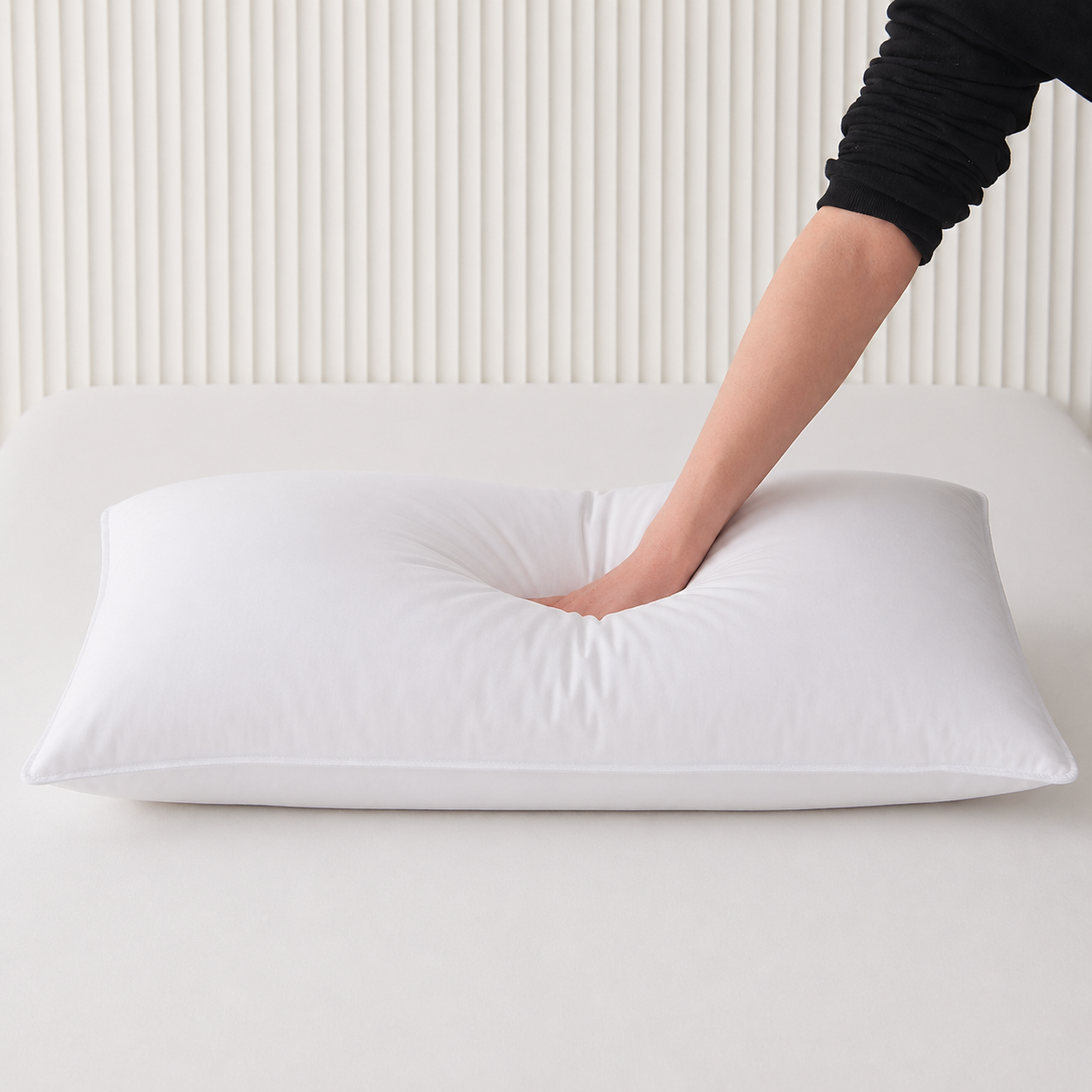 Hand pressing a Royal Elite Down Combo Pillow to show its balanced compression, loft and supportive feel.