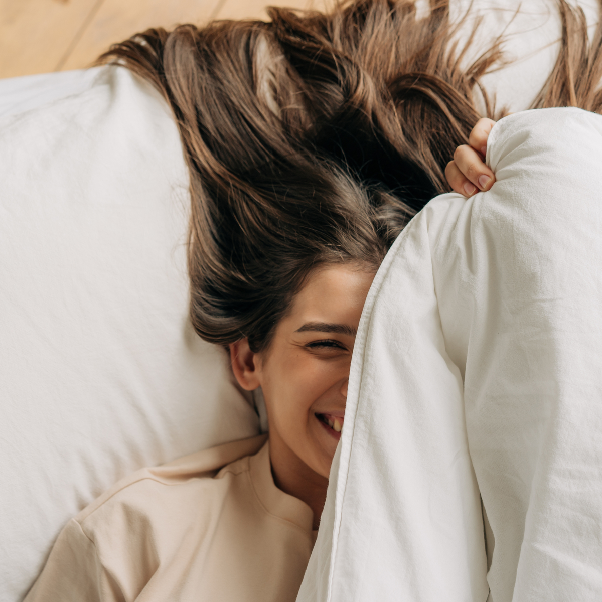 Woman relaxing in bed under a soft white Royal Elite duvet and comforter that are the best. Made in Canada and manufactured by Maholi Inc.