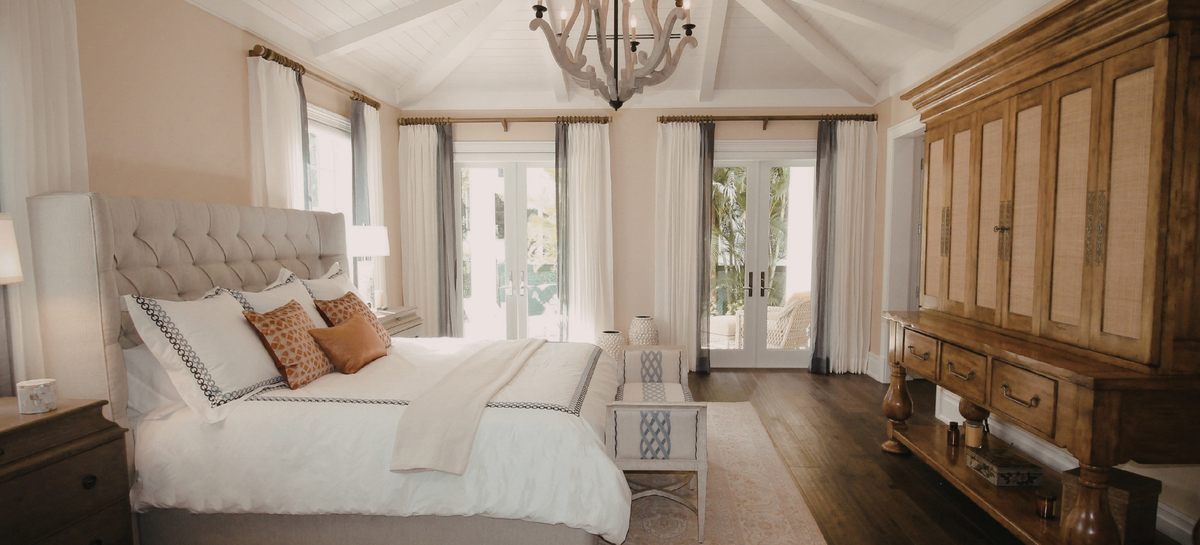 Warm neutral bedroom with white bedding and autumn-toned pillows for the Royal Elite Cozy Season Sale.
