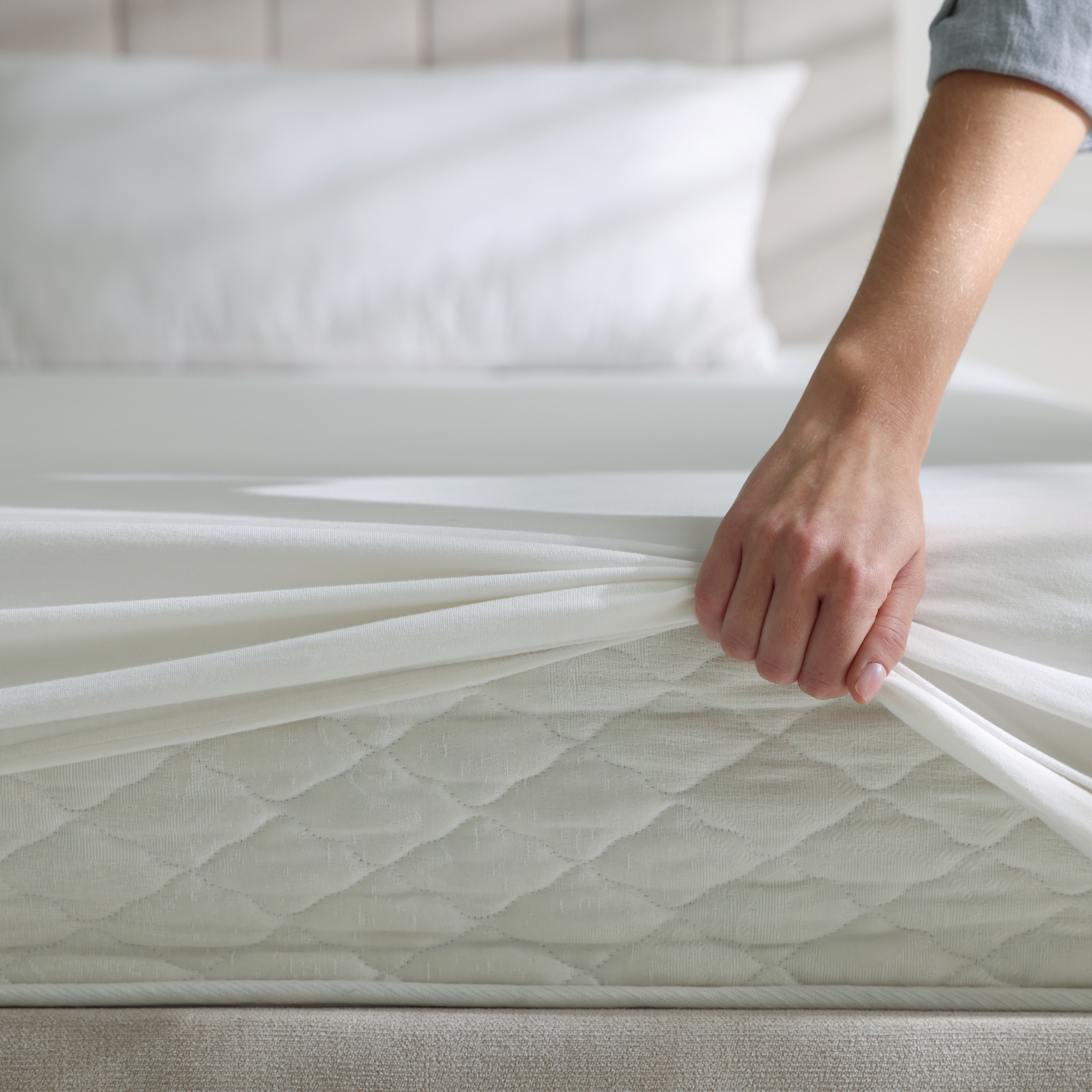 Hand pulling a fitted sheet over a mattress corner