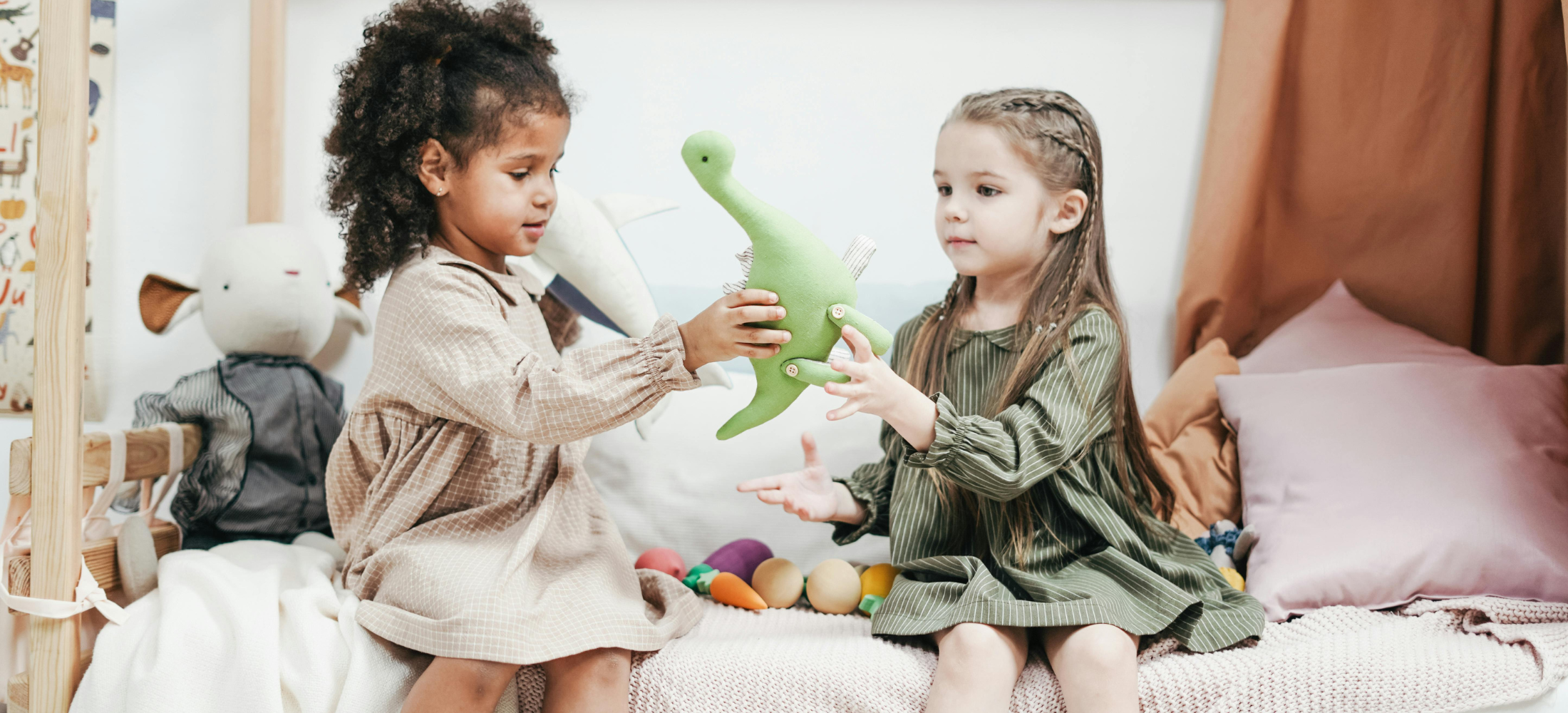 Two children playing with a stuffed dinosaur toy in a bedroom.