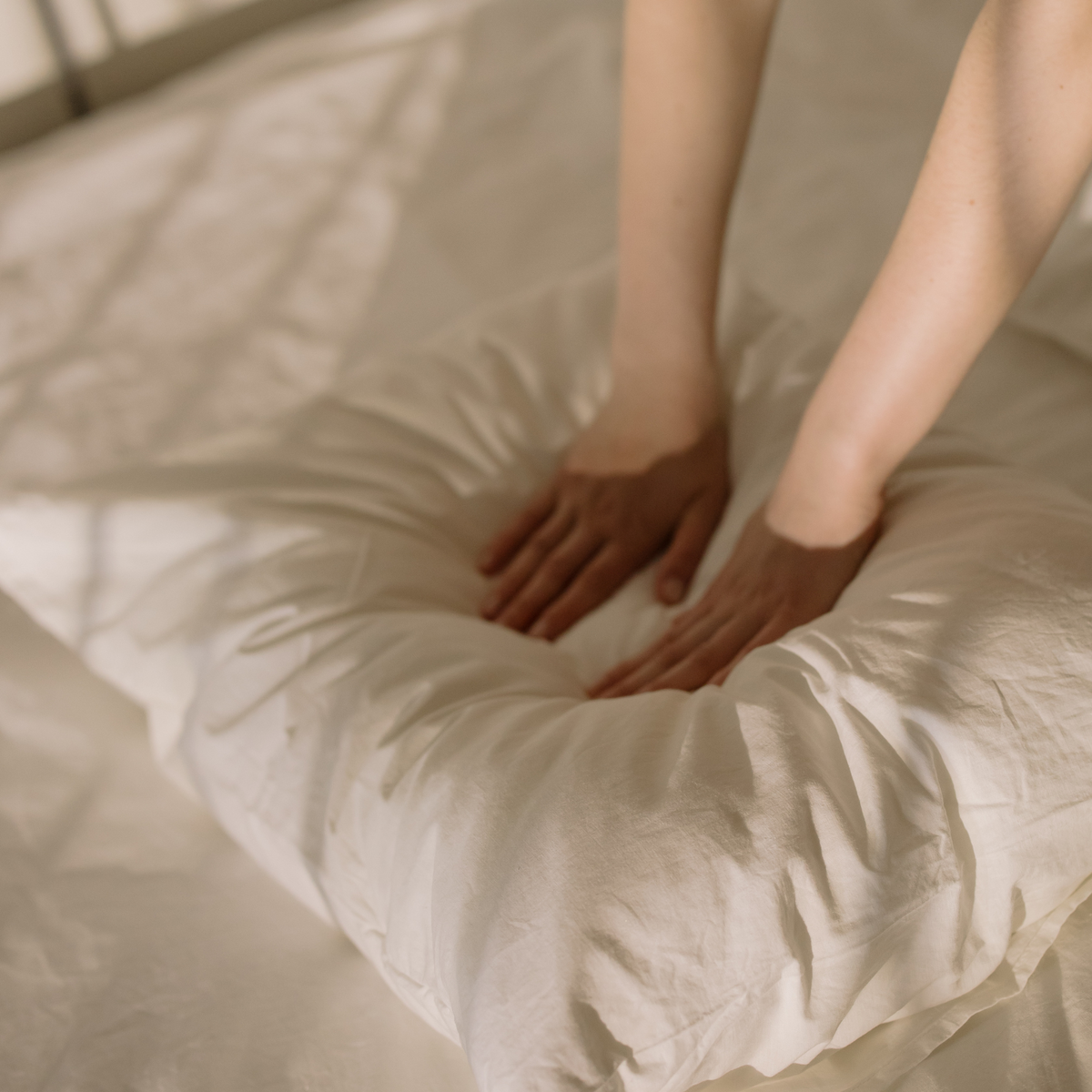 Hands pressing into a soft white Royal Elite pillow to show its plush comfort and loft. Royal Elite pillows are manufactured by Maholi Inc since 1994.